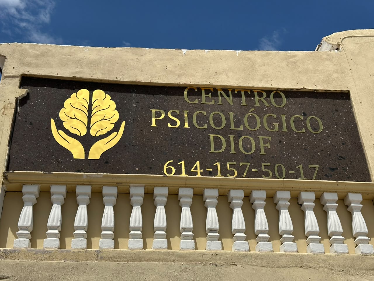 Letrero exterior del Centro Psicológico DIOF con logotipo de cerebro en manos y teléfono 614-157-50-17